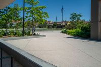 a person riding a skate board on the cement surface in front of a building and trees