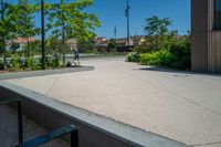 a person riding a skate board on the cement surface in front of a building and trees