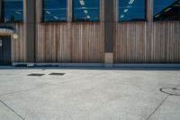 a parking meter on concrete outside a building with glass windows next to it and a wooden bench