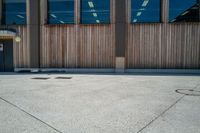 a parking meter on concrete outside a building with glass windows next to it and a wooden bench