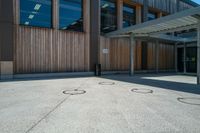 an open courtyard on a sunny day with three small circles in the cement at the corner