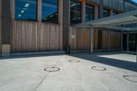 an open courtyard on a sunny day with three small circles in the cement at the corner