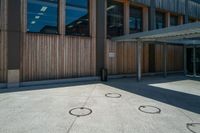 an open courtyard on a sunny day with three small circles in the cement at the corner