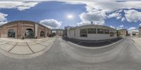 a fish eye view of a building and street and sky with clouds behind it on a clear day