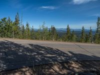 the mountains are visible in the distance from this wide, empty road, overlooking a wide landscape and forest