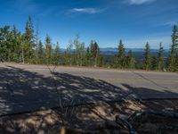 the mountains are visible in the distance from this wide, empty road, overlooking a wide landscape and forest