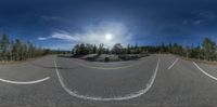 a 360 - lens picture of a road in the wilderness during a sunny day taken with a fish eye lens