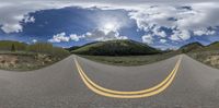 an empty road with three yellow lanes at the center of the image and a blue sky above the top