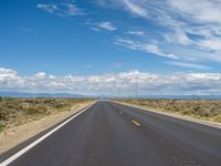 a highway stretching into the distance with mountains in the background in the distance is a line of yellow and white dotted lines