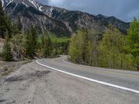 a curve road through a forest with a mountain range in the distance in the background