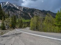 a curve road through a forest with a mountain range in the distance in the background