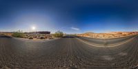 a panoramic view shows a curved asphalt road with mountains in the background and a bright moon rising