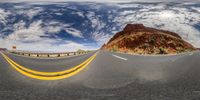 a curve shaped road with a blue sky behind it and yellow lines around the bottom