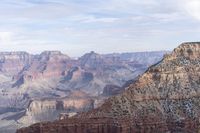 a large cliff surrounded by canyon covered in snow and rock formations is near the edge of a canyon