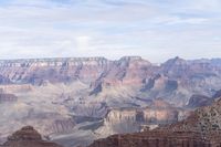 a large cliff surrounded by canyon covered in snow and rock formations is near the edge of a canyon