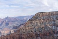 a large cliff surrounded by canyon covered in snow and rock formations is near the edge of a canyon