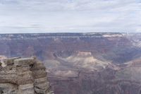 a large cliff surrounded by canyon covered in snow and rock formations is near the edge of a canyon