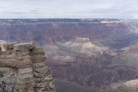 a large cliff surrounded by canyon covered in snow and rock formations is near the edge of a canyon