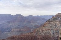 a large cliff surrounded by canyon covered in snow and rock formations is near the edge of a canyon