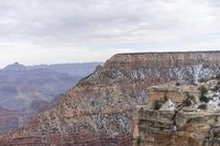 a large cliff surrounded by canyon covered in snow and rock formations is near the edge of a canyon