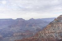 a large cliff surrounded by canyon covered in snow and rock formations is near the edge of a canyon