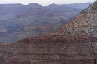 a large cliff surrounded by canyon covered in snow and rock formations is near the edge of a canyon