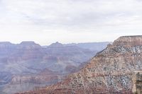 a large cliff surrounded by canyon covered in snow and rock formations is near the edge of a canyon