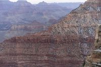 a large cliff surrounded by canyon covered in snow and rock formations is near the edge of a canyon