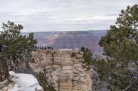 a large cliff surrounded by canyon covered in snow and rock formations is near the edge of a canyon