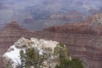 a large cliff surrounded by canyon covered in snow and rock formations is near the edge of a canyon