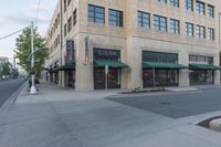 a street with a store and cars parked along it, and the sidewalk that is empty