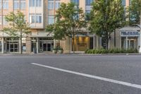 two streets and buildings with trees lined the curb and outside the building that is a large sign hanging above it