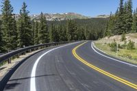 a curved highway with mountains on either side of it and white lines, in the distance