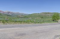 a yellow fire hydrant in the middle of a dirt road with mountains in the background