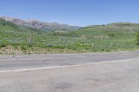 a yellow fire hydrant in the middle of a dirt road with mountains in the background