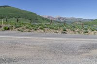 mountains in the background with trees, bushes and a road sign near a street sign