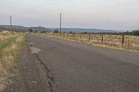 a long empty road with no sidewalks or buildings on it, with power poles in the distance