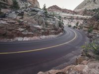 a winding, curved highway surrounded by mountains with a rock outcropping at the bottom