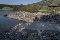 stone, concrete and wood pathway leading out onto the water and pavilion near the shore