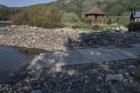 stone, concrete and wood pathway leading out onto the water and pavilion near the shore