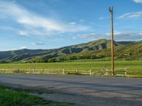 a lone country road is in the countryside area with mountains on both sides and barbed fence between the two sides