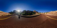 this 360 - view photo captures the curving road into the sun and the mountains behind it