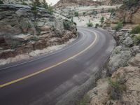 an empty roadway that leads to a canyon like cliff side trail surrounded by rugged rocks