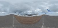 an image of two road in the middle of a mountain range with snow on top