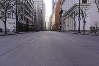 an empty city street in a big city with tall buildings and some cars on it