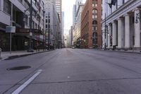 an empty city street in a big city with tall buildings and some cars on it