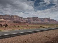 a man is riding his motorcycle down the side of the road next to mountains in arizona