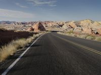 the view of the desert from an empty road with two people riding motorcycles across it