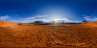 a photograph taken from a fisheye lens of the desert with a sun behind it