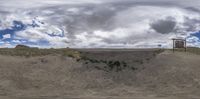 a view of a dirt road in the desert on a cloudy day with clouds overhead